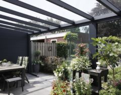 Sfeervolle antractiete terrasoverkapping met glaswanden, tuinset en planten