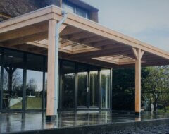 Moderne grote houten terrasoverkapping aan huis met dubbele lichtstraat