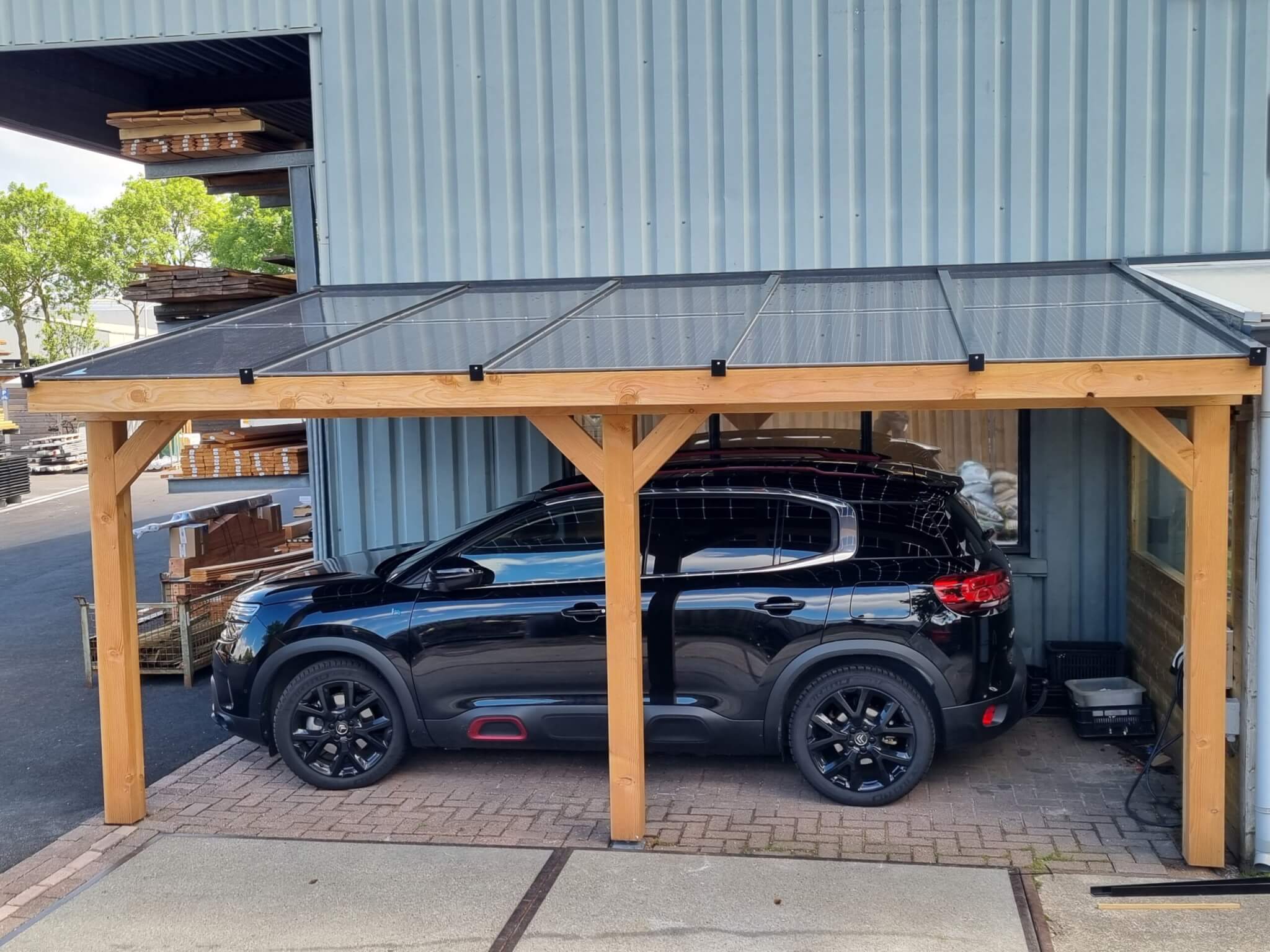 carport van hout met zonnepanelen met auto eronder