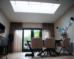 Moderne woonkamer met visgraatvloer zwarte openslaande deuren en lichtstraat