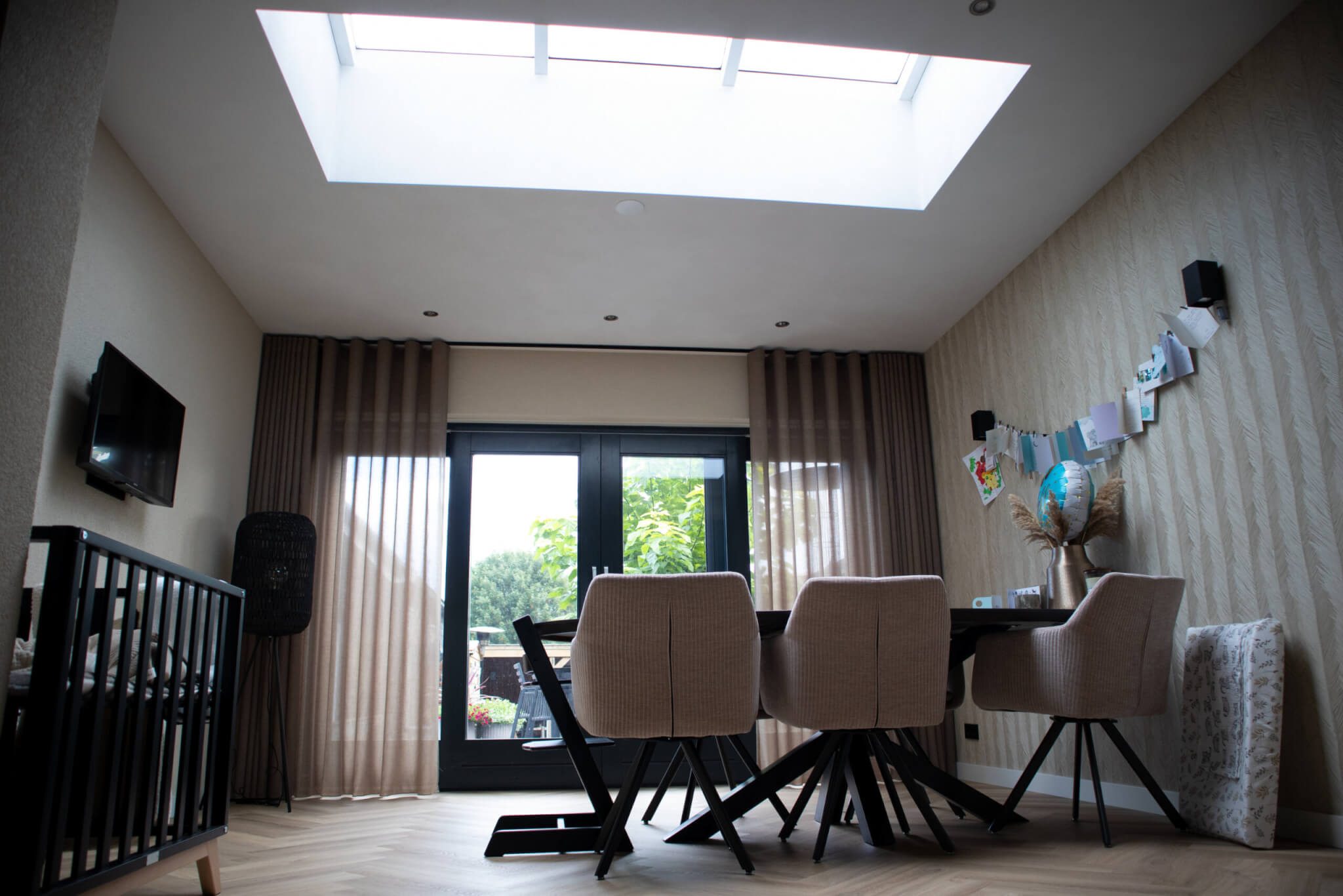 Moderne woonkamer met visgraatvloer zwarte openslaande deuren en lichtstraat