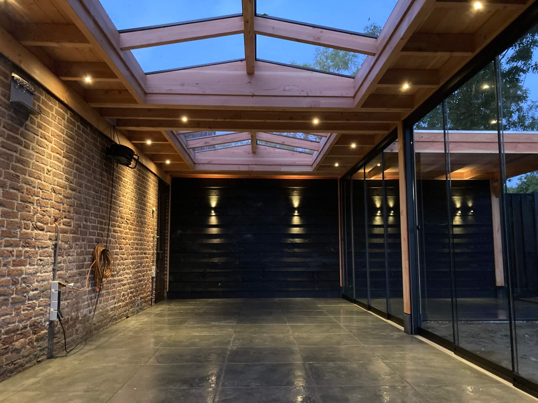 Terrsoverkapping muuraanbouw met dubbele zadeldak lichtstraat en antraciet glazen schuifwanden