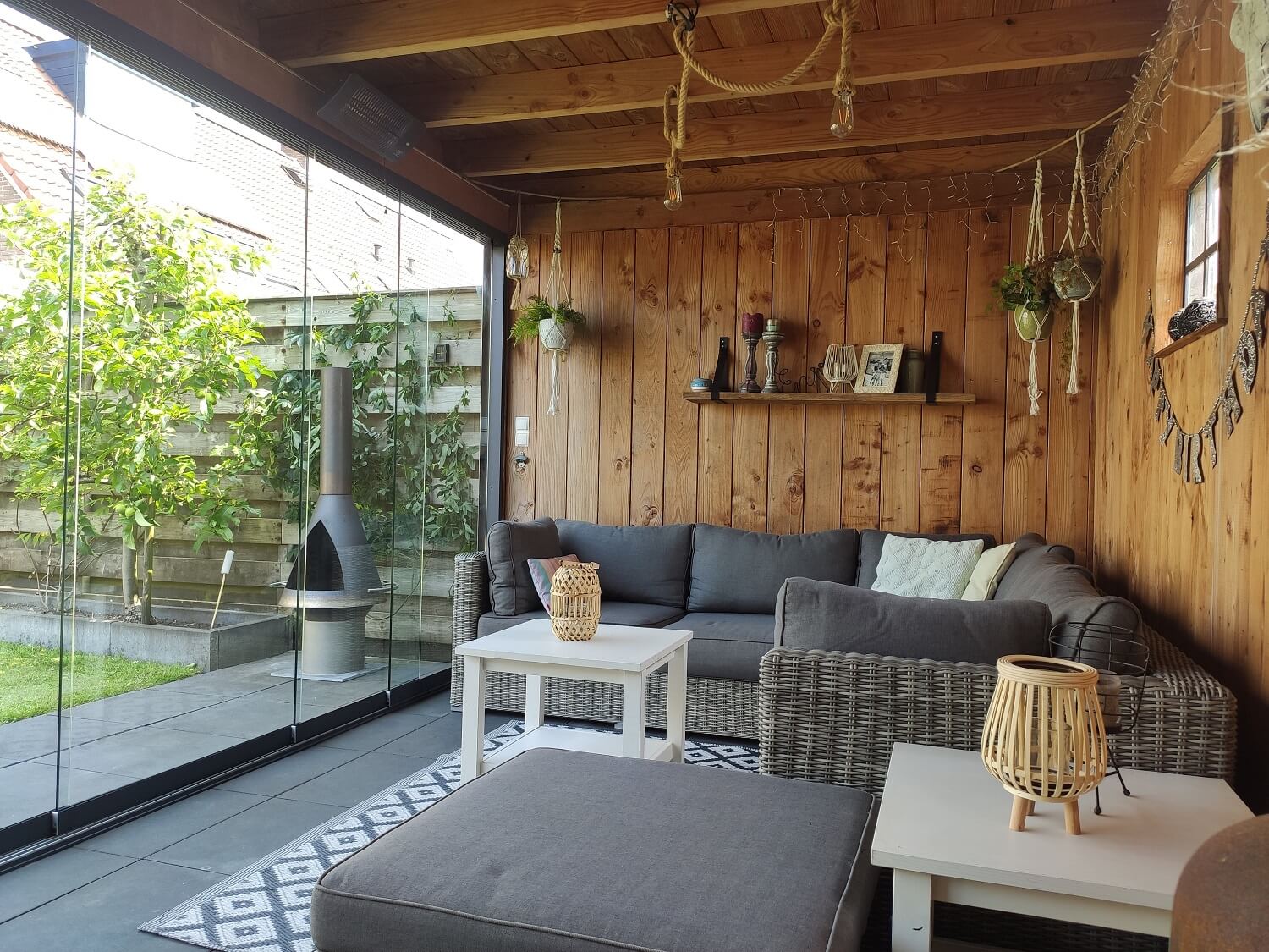 Gezellige houten overkapping met accessoires, tuinset en glazen schuifwanden