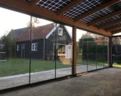 Overkapping met zonnepanelen muuraanbouw met glazen schuifwanden